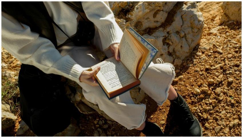 A person relaxing and reading a book outdoors on a
