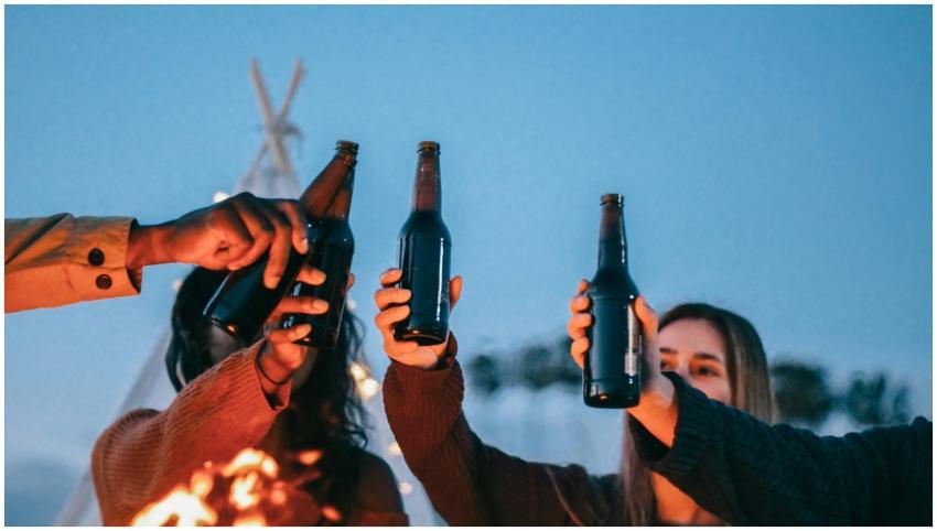 A group of friends toasting with beer bottles arou