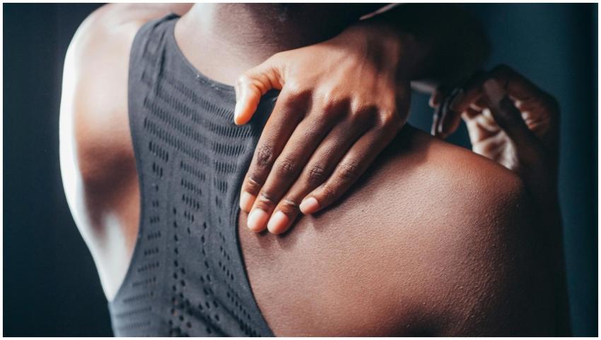 Close-up of a person holding their shoulder, weari