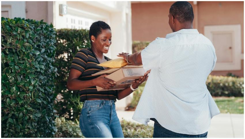 A smiling woman receives multiple packages from a