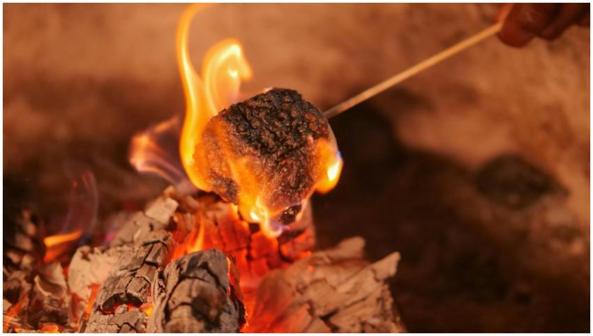 A close-up view of a marshmallow roasting over a c