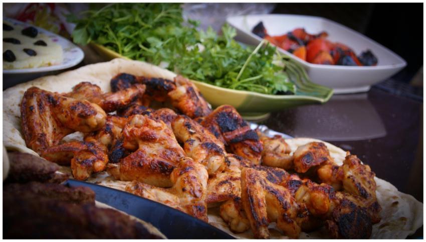 A close-up of grilled chicken wings served with fr