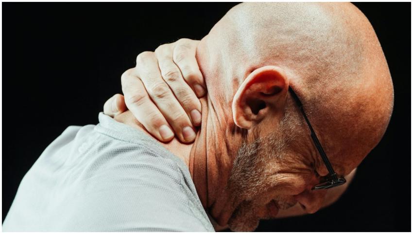 Side view of senior man holding neck with visible