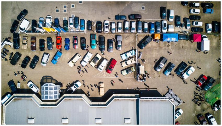Drone shot showing cars and people in a parking lo