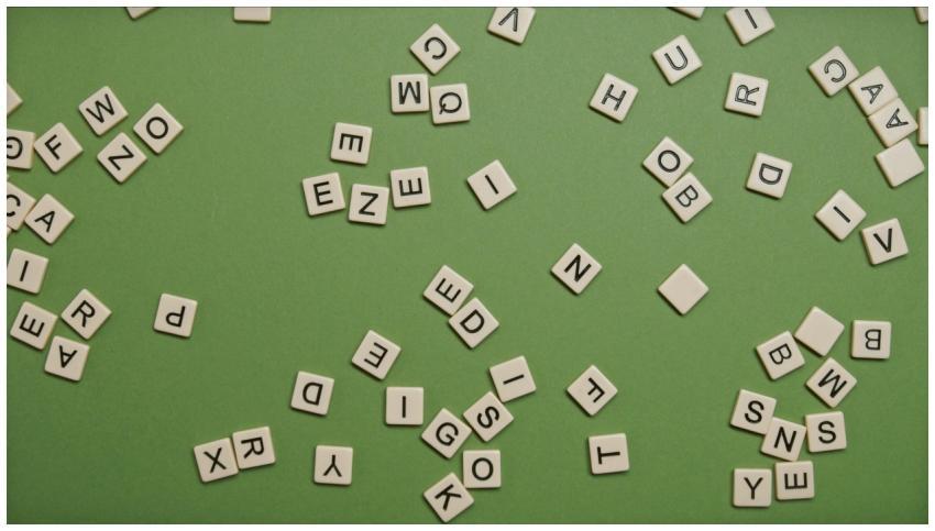 Scattered alphabet tiles on a green background, pe