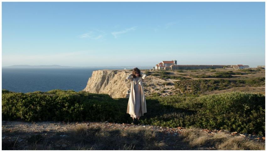 Woman standing near cliffs with ocean vista, highl
