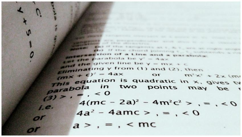 A close-up shot of mathematical equations on a boo