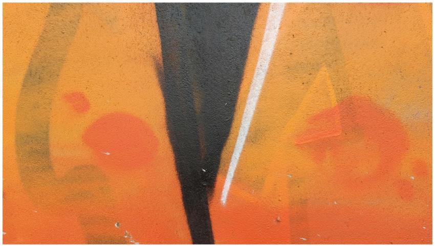 Bold abstract graffiti with orange tones on a conc