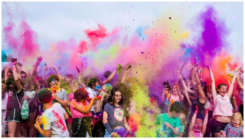 A joyful crowd covered in vivid colors celebrates