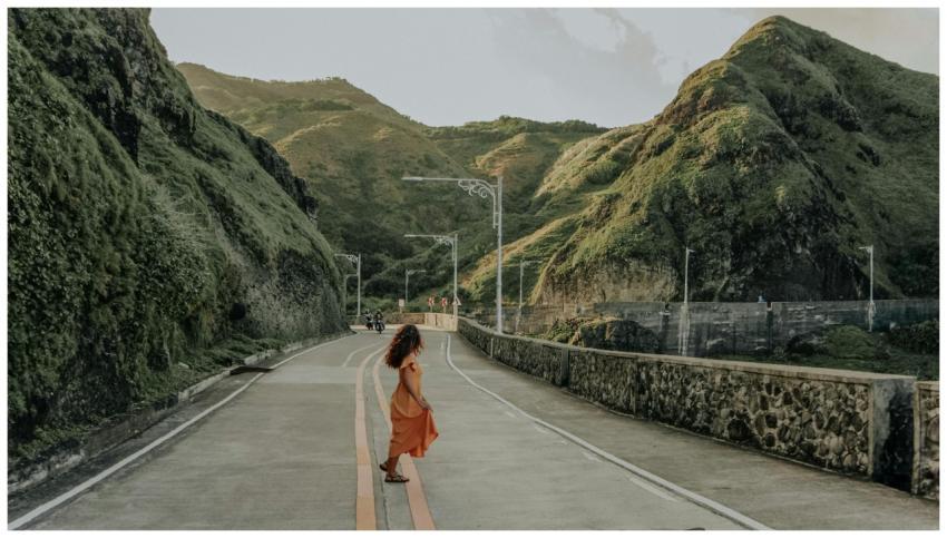 A woman strolls on a scenic mountain road in Cagay