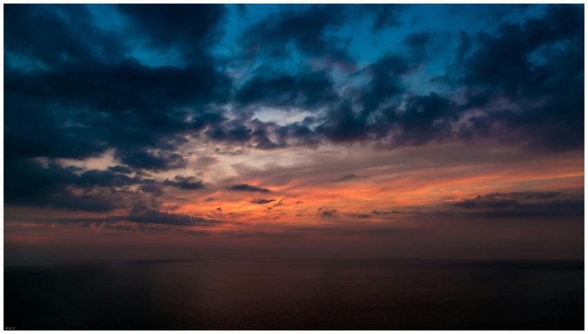 A vibrant sunset with dramatic clouds over a calm