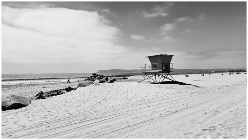 A serene black and white image of a beach with a l