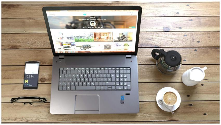 Top view of a laptop, smartphone, coffee, and glas