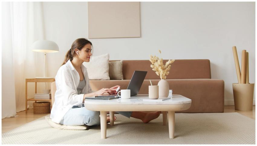A woman uses a laptop at a coffee table in a cozy