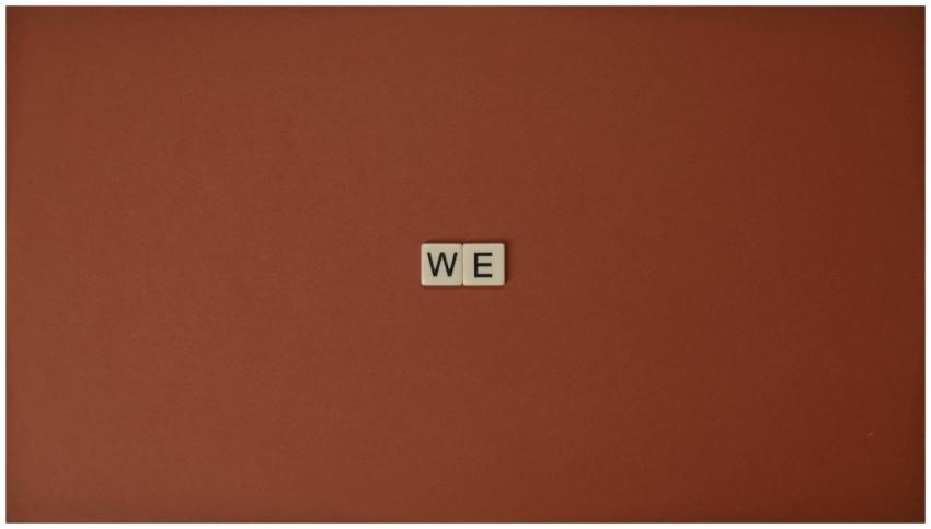 Close-up of Scrabble tiles spelling 'WE' on a brow