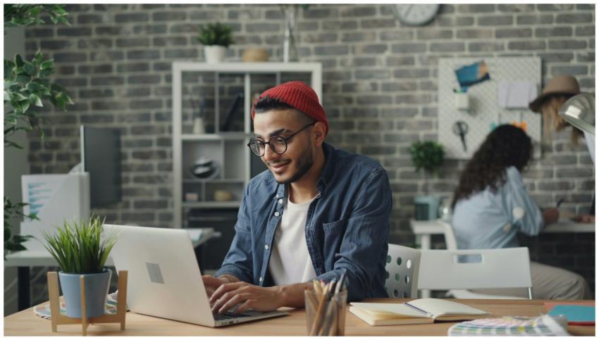 A young man in a beanie working diligently on a la