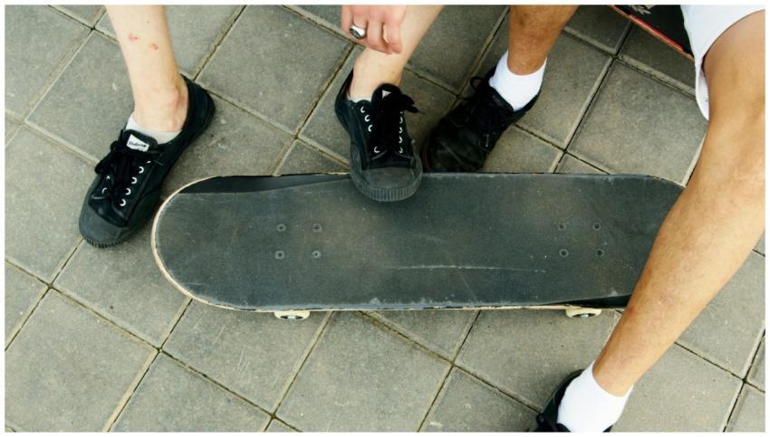 Close-up of teenagers' legs and skateboard on pave