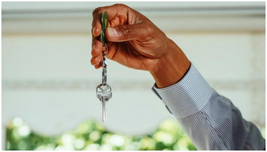 A hand holding a set of house keys, symbolizing bu