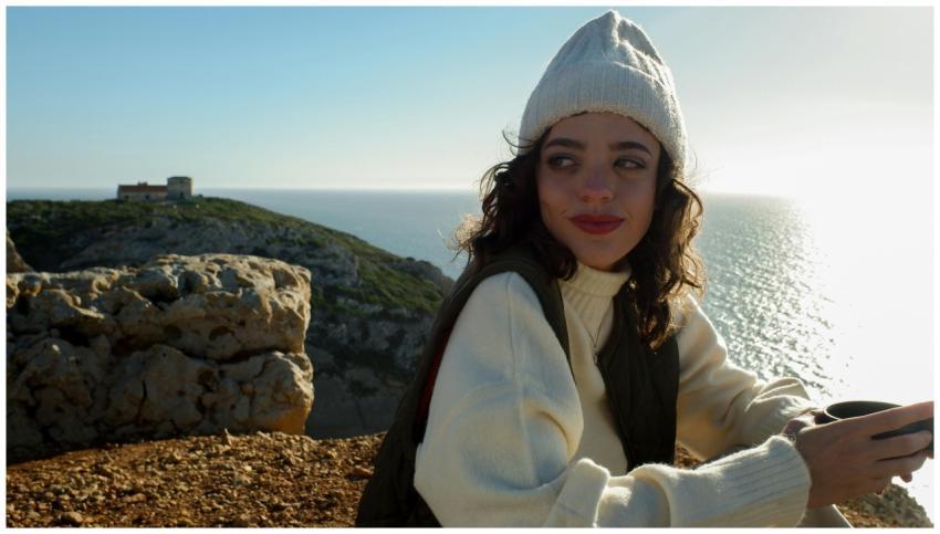 Woman wearing a knit cap and white sweater enjoyin