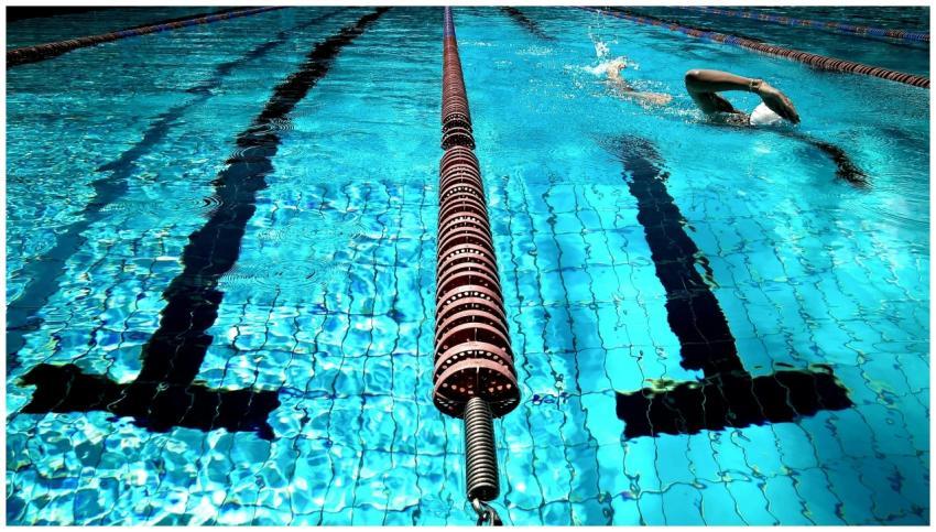 A person swimming in a clear blue outdoor pool wit