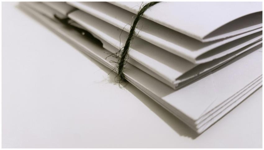 Pile of white envelopes tied with a green string,