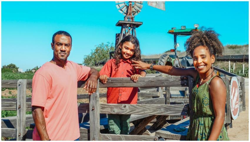 Smiling family of three at the farm, with windmill