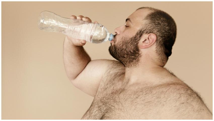 Bearded man drinking water from plastic bottle to