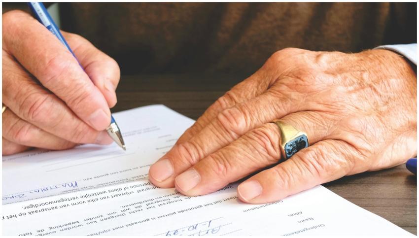 Close-up of a senior adult signing a legal documen