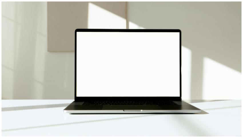 A laptop with a blank white screen on a desk, bath