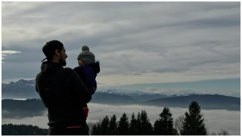 A father holds his child while viewing a scenic wi