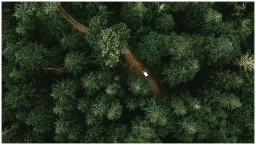 A drone shot capturing a car traveling on a seclud