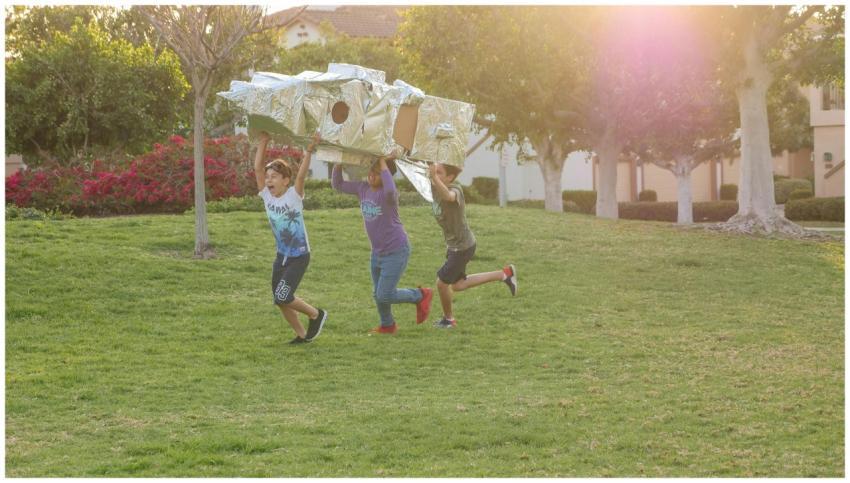 Three children enjoy imaginative play outdoors wit