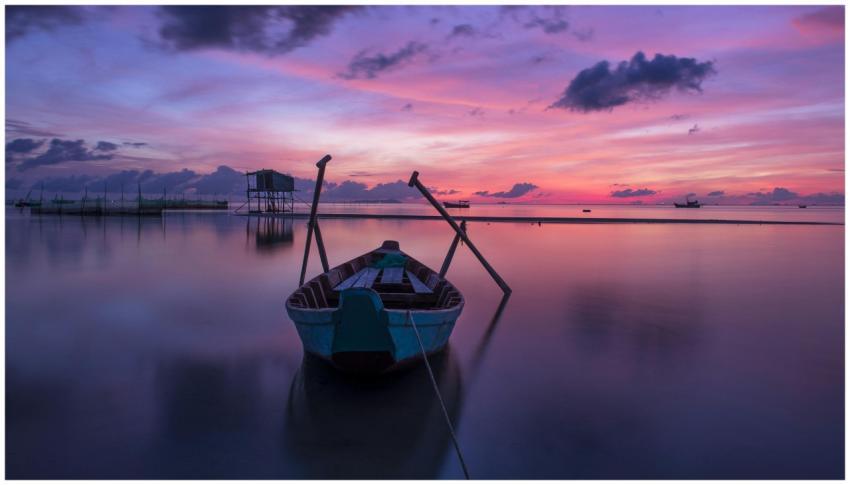 A serene boat reflecting on calm ocean waters duri