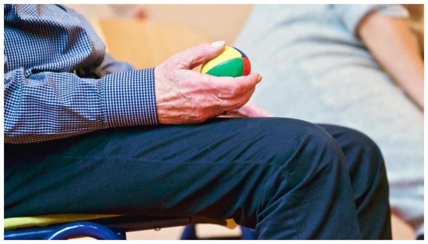 Elderly man holding a colorful therapy ball indoor