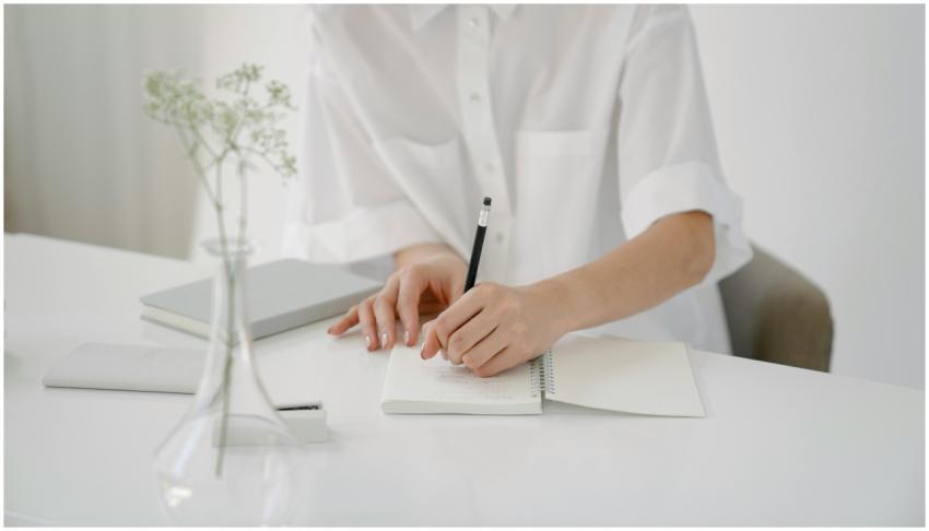A woman writing in a notebook at a minimalist desk