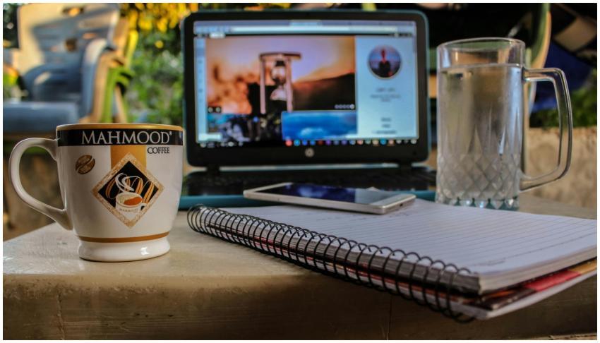 Outdoor workspace setup with coffee, laptop, and n
