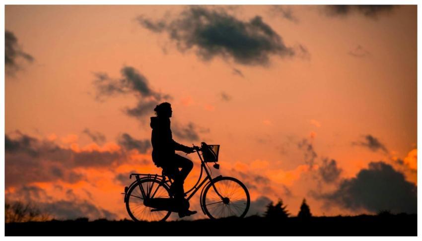A cyclist rides against a vibrant sunset, capturin