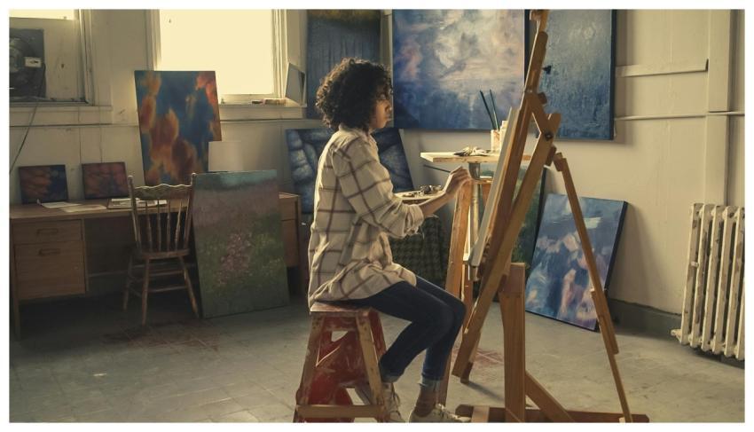 A young woman focused on painting in an art studio