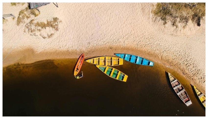 Aerial shot of vibrant boats on a sandy beach in B