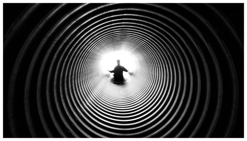 A person silhouetted against light at the end of a