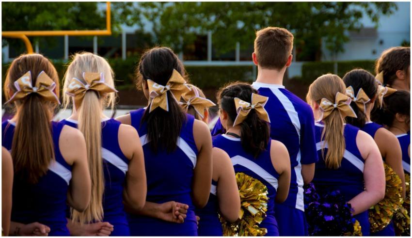 Rear view of cheerleaders in uniform outdoors, pre
