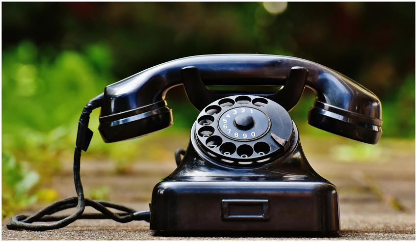 Close-up of a classic black rotary phone outdoors
