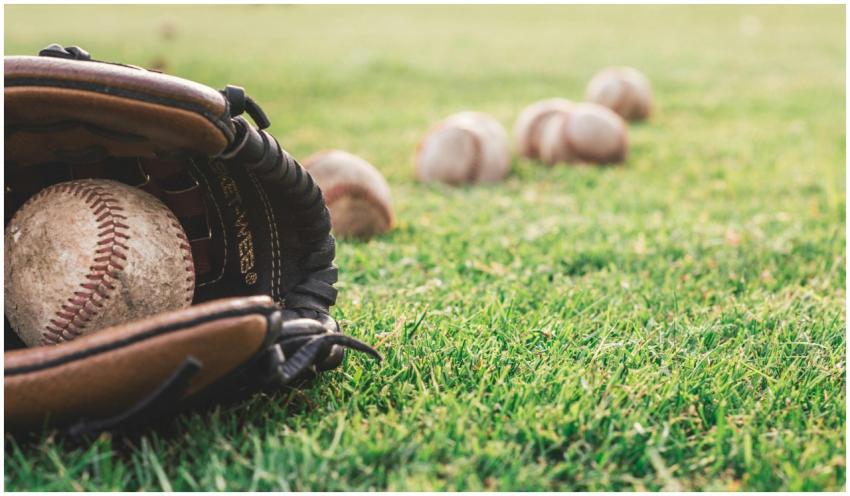 A close-up of a baseball glove with balls on a gre