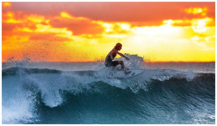 Surfer riding a wave during a stunning sunset, cap