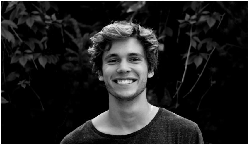 A black and white portrait of a young man smiling