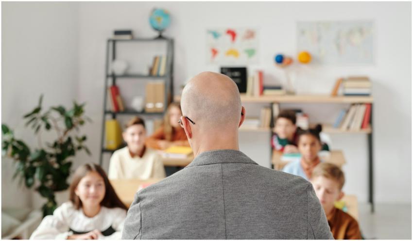Bald teacher in a classroom engaging with attentiv