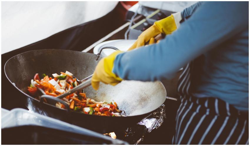 A chef stir-frying vegetables in a wok, showcasing