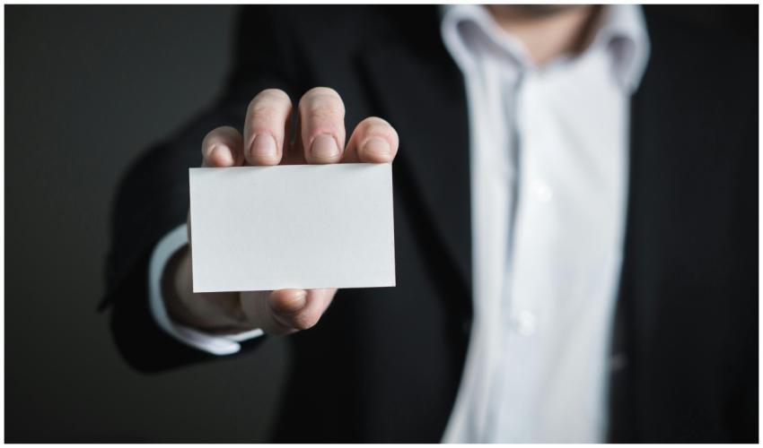 A man in a suit presenting a blank business card f