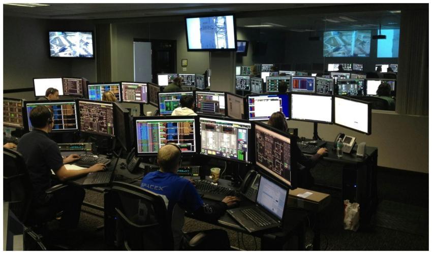 A bustling control room with people working on mul