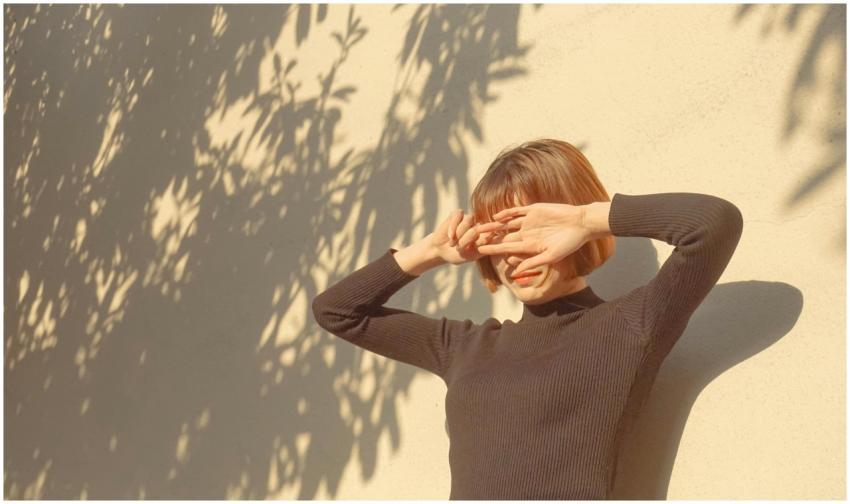 A stylish woman covers her eyes from the sun, enjo